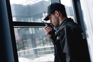 handsome-guard-in-black-uniform-talking-on-walkie-2022-12-16-19-33-25-utc